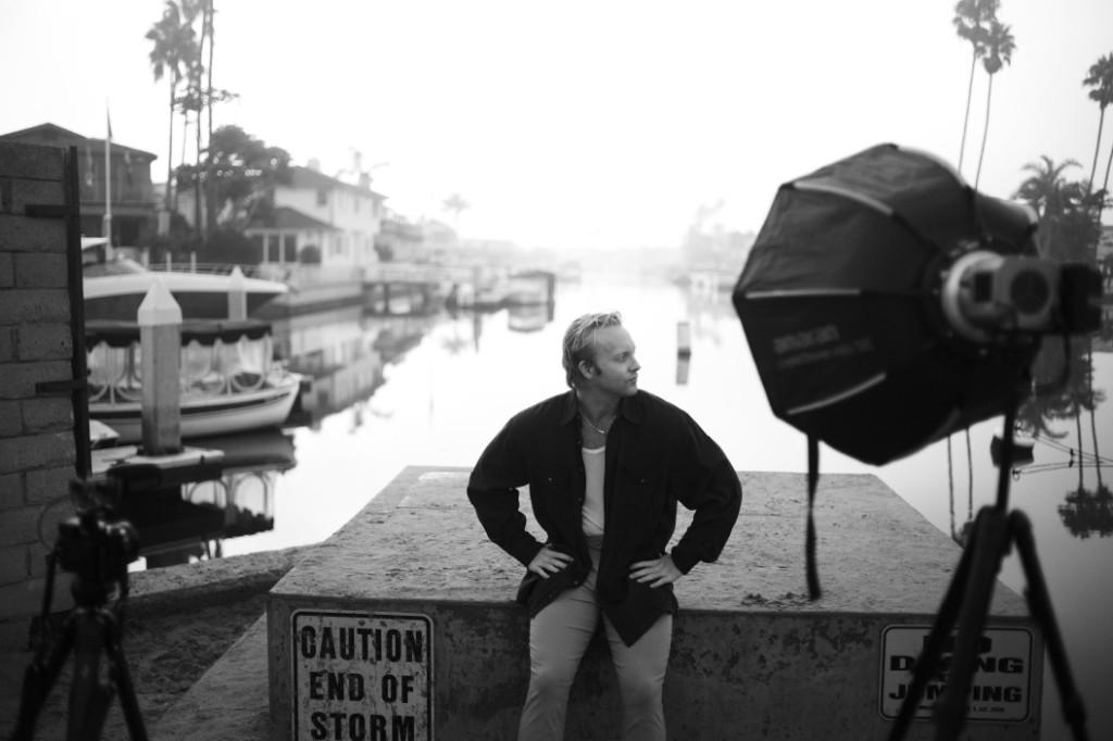 Luke Lively seated on a dock during a black-and-white waterfront photoshoot