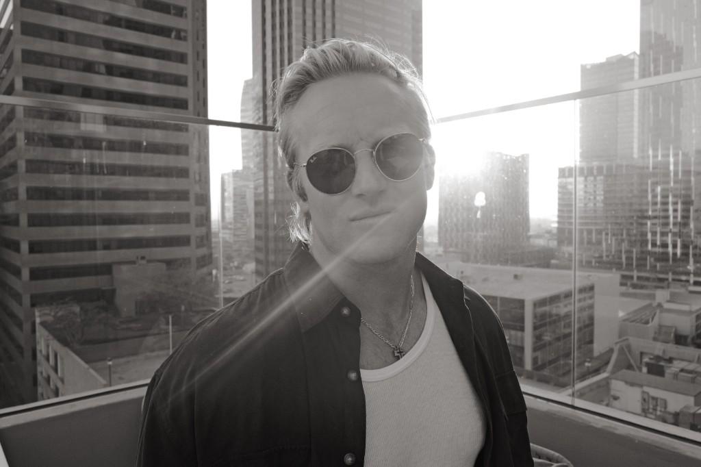 Luke Lively wearing sunglasses on a rooftop in a black-and-white city portrait